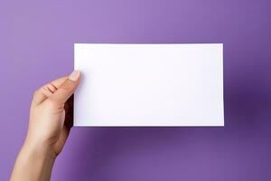 A human hand holding a blank sheet of white paper or card isolated on purple background. ai generated photo