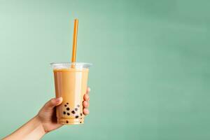 A hand holding takeaway plastic cup of delicious iced bubble milk tea and black pearls with copy space. ai generated photo