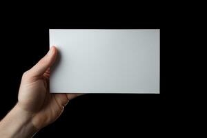 A human hand holding a blank sheet of white paper or card isolated on black background. ai generated photo