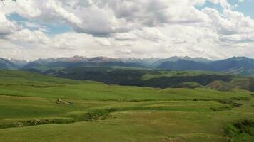 Mountain peaks and grassland are under white clouds. video