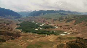 Mountain peaks and grassland are under white clouds. video