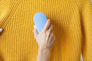 woman in yellow sweater using fabric pills removing tool photo