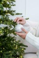 female hand in white sweater decorating christmas tree photo