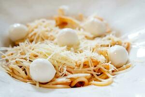 delicious spaghetti with mozarella balls and tomato sauce on wooden table in cafe photo