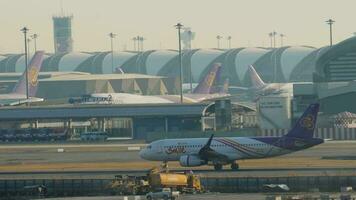 bangkok, Tailandia gennaio 21, 2023 - commerciale aereo airbus a320 di tailandese Sorridi rullaggio a suvarnabhumi aeroporto. riga di aerei attraccato per il terminale. Visualizza di il campo di aviazione di un' moderno aeroporto video