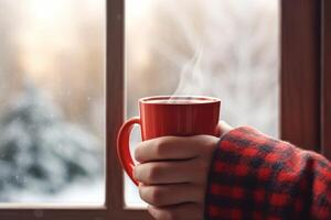 Hand holding Cup of hot tea on window, red plaid and curtain , rain outside. AI Generated photo