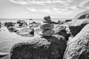 Stone pyramid on the coast of the Baltic Sea overlooking the sea in black and white. photo