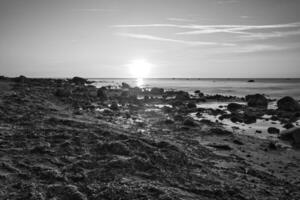 Sunset, stone beach with small and large rocks in black and white. photo