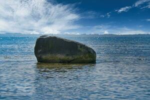 Single stone, rock in the Baltic Sea in sunshine. Landscape photo from coast.