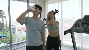 Young Asian Couple Drinking Water After Workout at Gym video