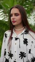 young brunette girl looks into the camera against the background of palm trees video