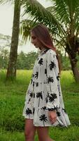 vertical video young girl with dark hair walks among palm trees
