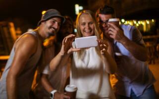 Happy friends making phone selfie at night photo