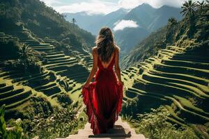 un joven hembra turista en un rojo vestir admirativo el asombroso tegalalang arroz terraza en bali Indonesia foto