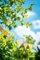 Colorful pennant string decoration in green tree foliage against blue sky summer party background with space for text photo