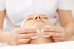 Cosmetician cleaning face using cotton pads photo