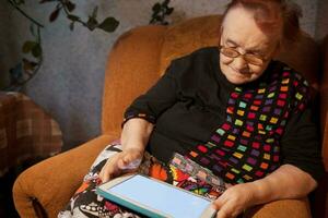 Elderly lady sitting in an chair using a tablet photo