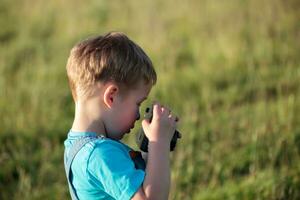 pequeño chico con cámara al aire libre foto