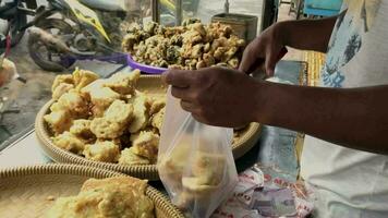 Magelang,indonesia.03 01 2023-a man is packing fried tempe merchandise to be given to buyers. video