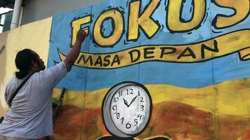magelang, indonésio, 2023-masculino grafite artista desenha uma ampla rua arte pintura com azul e amarelo. video