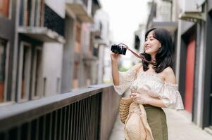 Happy youth asian woman with camera travels street city trip on leisure weekend. Young hipster female tourist sightseeing summer urban Bangkok destination. Asia summer tourism concept. photo