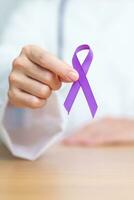 Doctor holding purple Ribbon for Violence, Pancreatic, Esophageal, Testicular cancer, Alzheimer, epilepsy, lupus, Sarcoidosis and Fibromyalgia. Awareness month and World cancer day concept photo