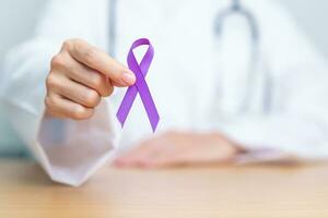 Doctor holding purple Ribbon for Violence, Pancreatic, Esophageal, Testicular cancer, Alzheimer, epilepsy, lupus, Sarcoidosis and Fibromyalgia. Awareness month and World cancer day concept photo