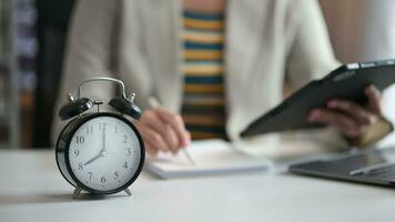 Alarm clock on the desk. Business hand using smartphone, laptop and tablet  working in modern office building or home video