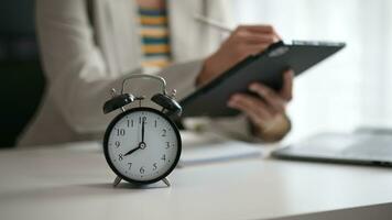 Alarm clock on the desk. Business hand using smartphone, laptop and tablet  working in modern office building or home video