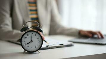 Alarm clock on the desk. Business hand using smartphone, laptop and tablet  working in modern office building or home video