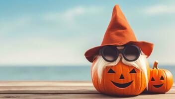 Halloween pumpkins with hat and sunglasses on wooden table with sea background photo