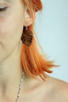 Red haired girl with Craft Wooden earring. Photography of Jewelry. Boho or Rustic Monstera leaf dangles. Redhead hairstyle model. Natural Beauty and eco concept. photo