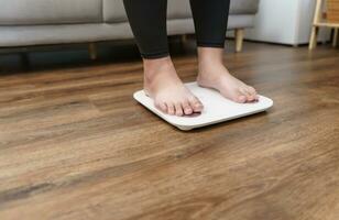 Fat diet and scale feet standing on electronic scales for weight control. Measurement instrument in kilogram for a diet control. photo