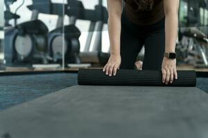 Fitness woman folding exercise mat before working out in yoga studio. rolling Yoga mat  after training healthy lifestyle photo