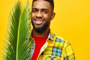 Afro man in a yellow shirt holding a palm leaf photo