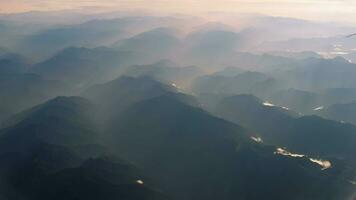 hermosa ver mediante avión ventana, avión volador encima brumoso montañas. China territorio. video