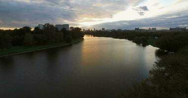 An aerial evening view of a wide river surrounded by dark tree crowns video