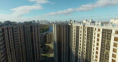 An aerial view of a large modern residential building and a sunny urbanscape behind it video