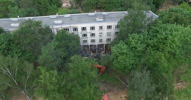 An aerial view of a half demolished building among green trees video