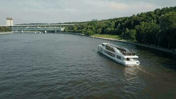 An aerial view of a boat slowly moving on urban river on a sunny day video