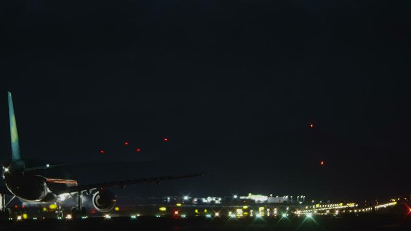 A plane moving on a runway against the pitch black night sky 