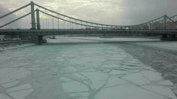 een bevroren rivier- oppervlakte en een brug bovenstaand het in de midden- van een winter urbanscape video