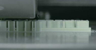 Extreme close up view of mechanism of 3d printer making white plastic object video