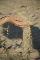close-up of hands with sand falling on a  beach photo