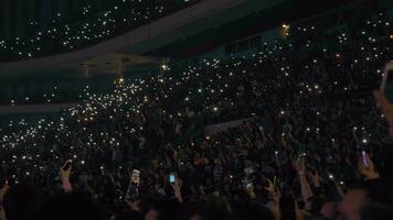 People waving cell flashlights at the music concert video