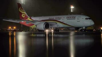 Hainan companhias aéreas boeing 787-8 delineador estacionado dentro a aeroporto às noite video