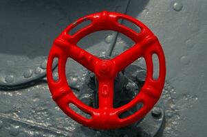 beautiful old red metal wheel for closing the door on a ship on a gray background, photo