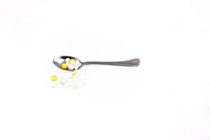 silver spoon with medicine lying on a white isolated background photo