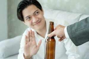 hombre sonrisa y se niega decir No y evitar a bebida un alcohol , mano espectáculo rechazar y parada, alcoholismo tratamiento, alcohol adiccion, dejar bebida alcohólica, detener Bebiendo alcohol. negar botella espíritu, insalubre foto