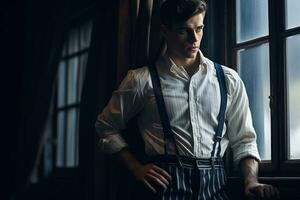 scene of a brutal young detective standing by the window with a thoughtful expression on his face and smoking a cigarette, he is wearing a striped shirt, classic pants with suspenders. AI Generated photo